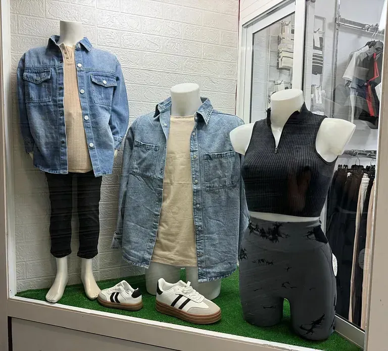 Una exhibición de ropa en maniquíes en el escaparate de una tienda.