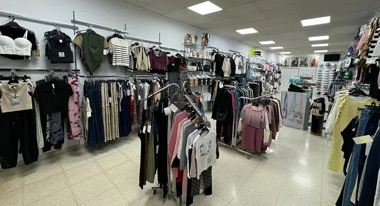 Una tienda llena de ropa colgada en percheros.
