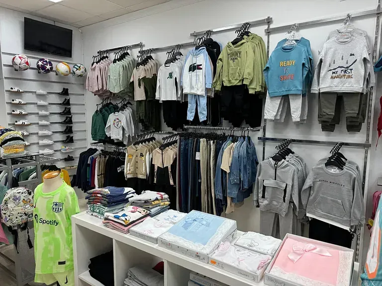 Una tienda llena de ropa para niños y un maniquí.