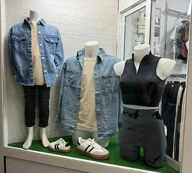 Una vitrina con tres maniquíes vestidos con ropa en el escaparate de una tienda.