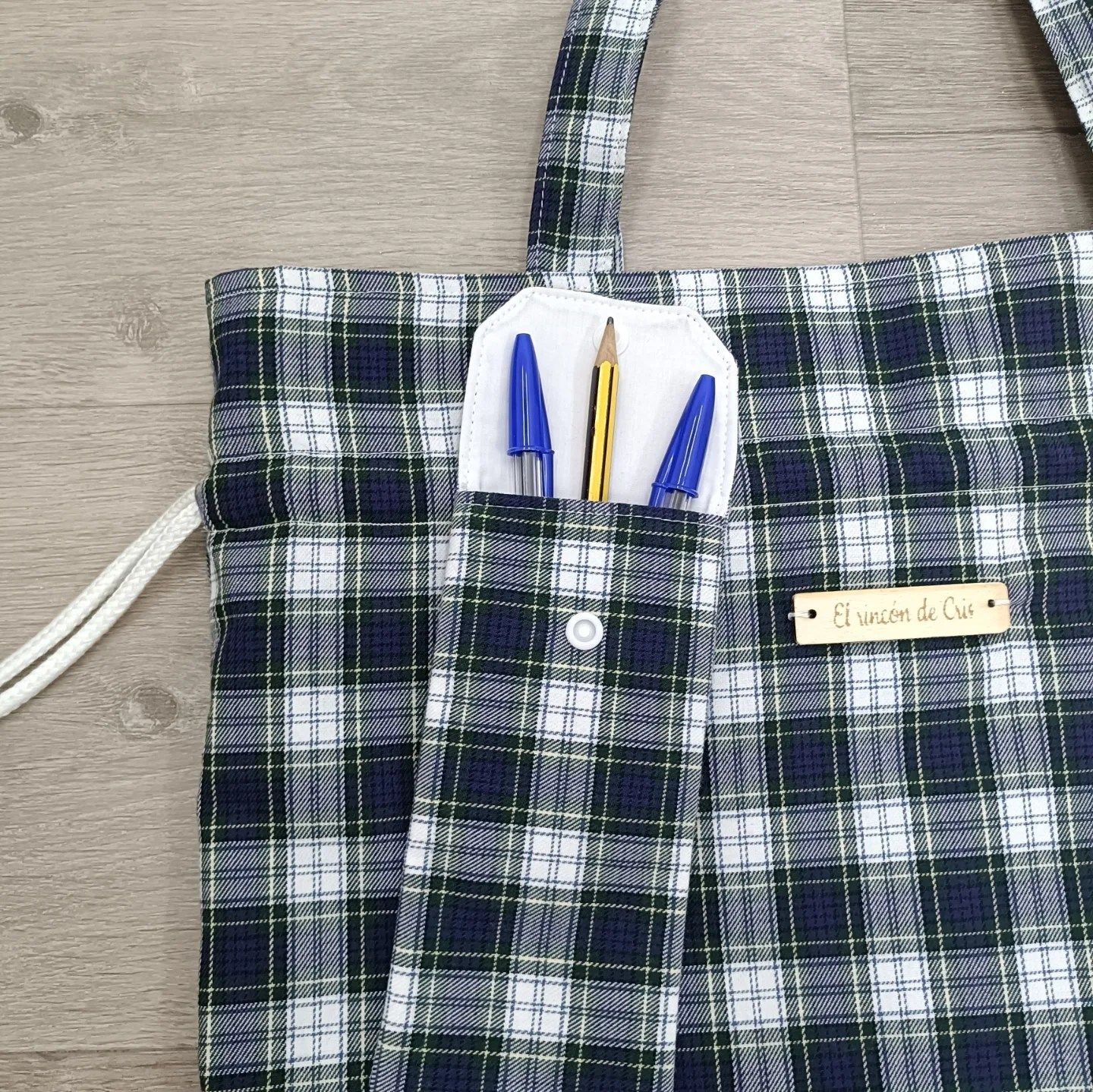 Una bolsa de mano a cuadros con dos bolígrafos y un lápiz dentro.