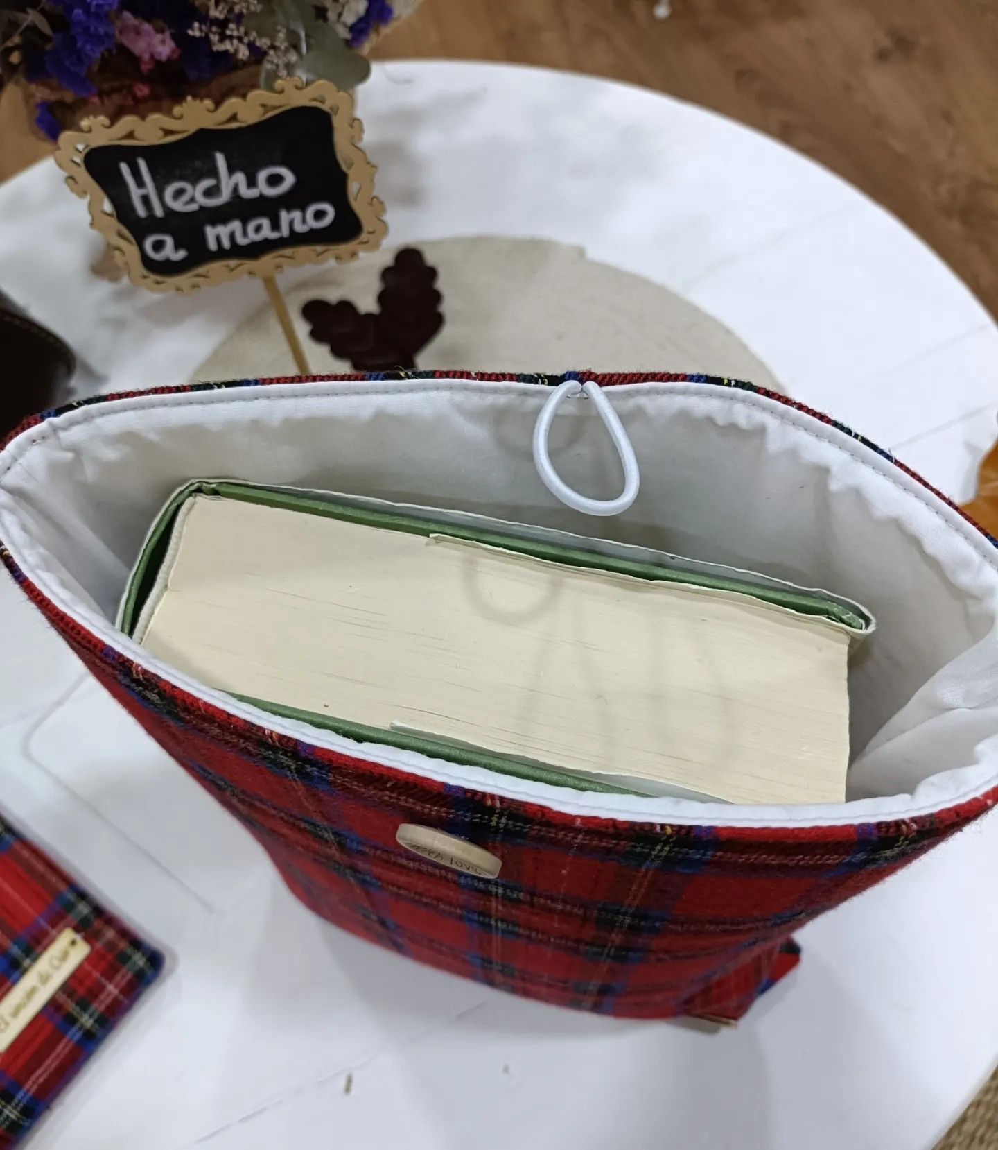Una bolsa a cuadros con un libro dentro y un cartel que dice
