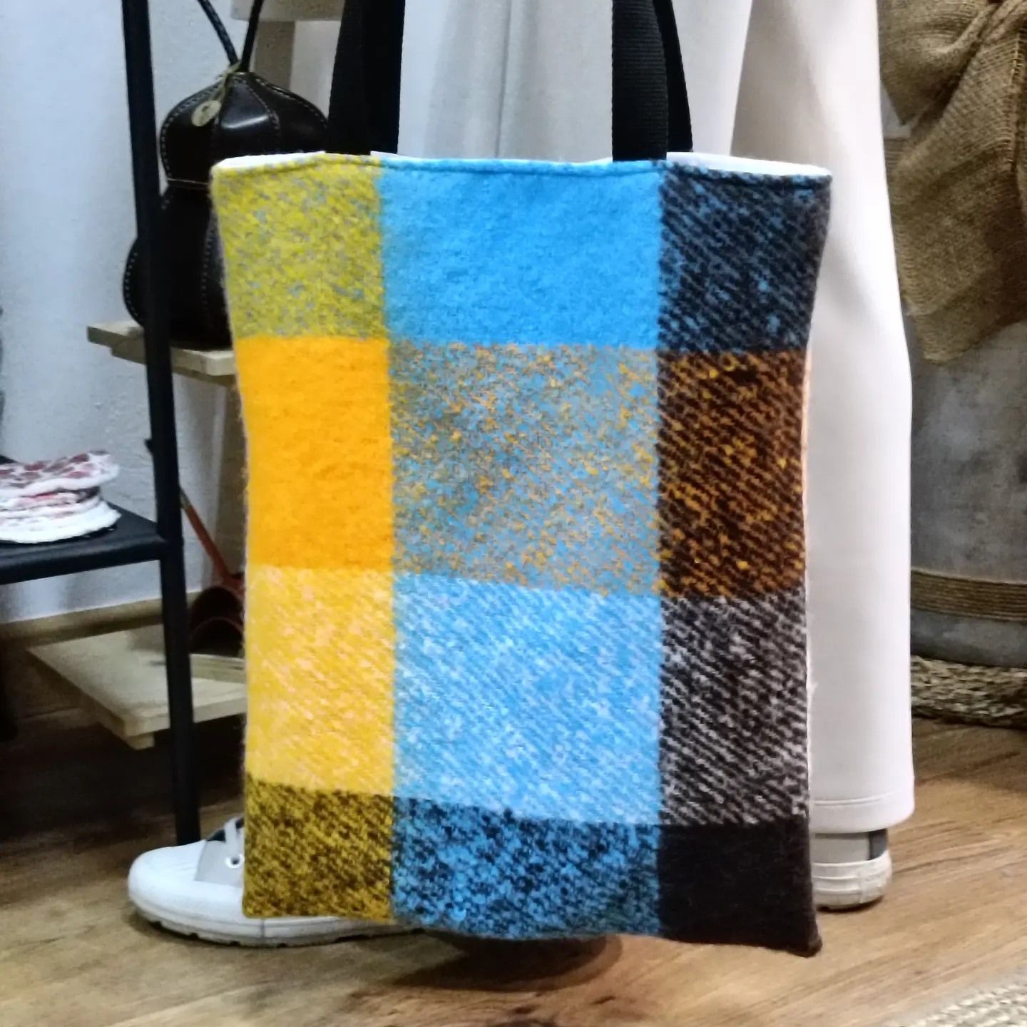 Una persona sostiene una bolsa de mano a cuadros azules y amarillos.