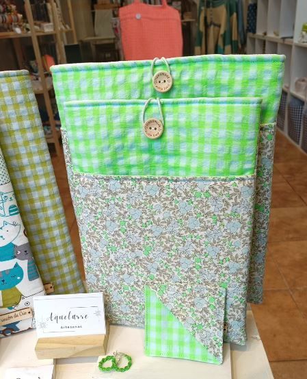 Un bolso de cuadros verdes con botones en el frente está sobre una mesa.