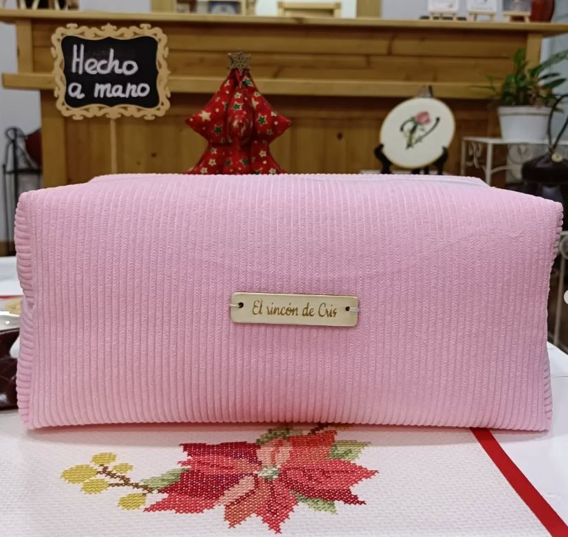 Un bolso rosa reposa sobre una mesa frente a un cartel que dice 