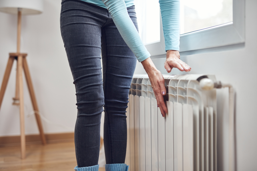 Femme posant ses mains sur un radiateur à côté d'une fenêtre