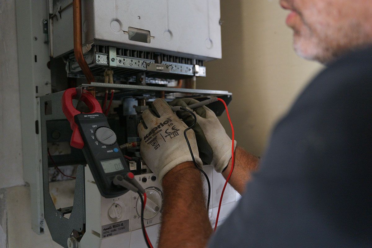 Technicien qui teste le courant dans une chaudière gaz