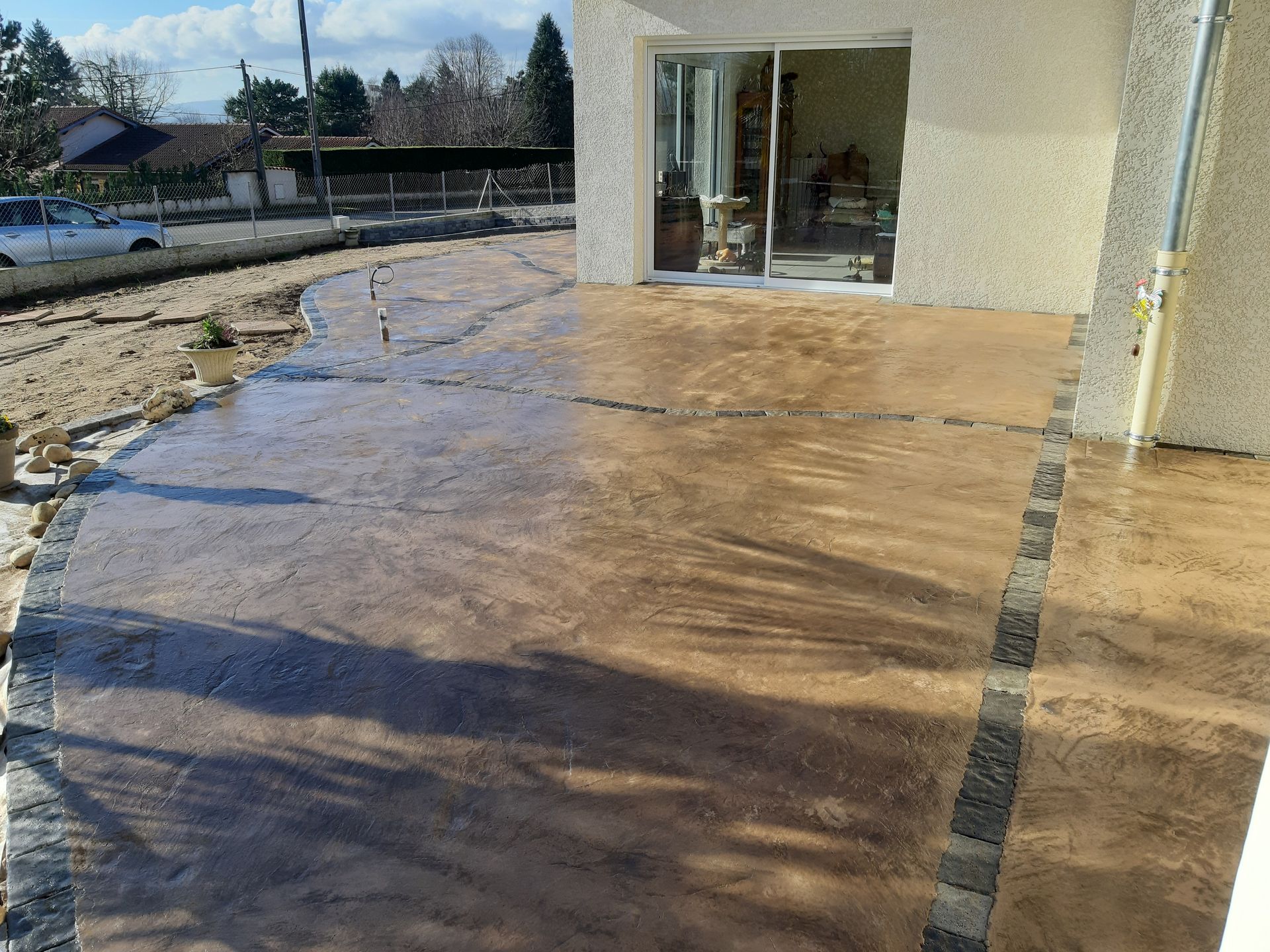 Eau de crue stagnante sur une terrasse en béton à côté d'un bâtiment, avec des débris boueux et des reflets.