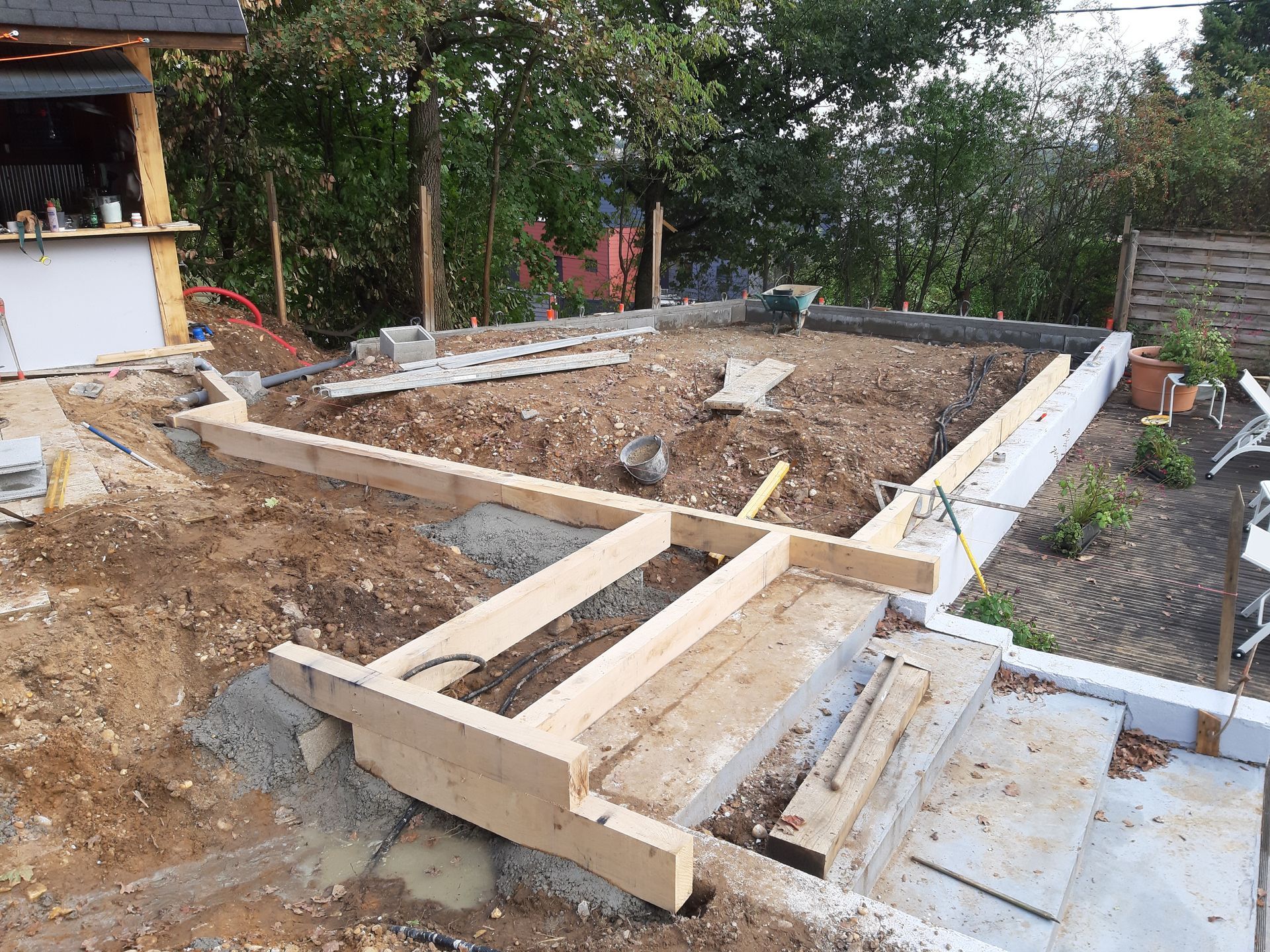 Chantier de construction avec ossature en bois autour d'une excavation dans une cour arrière