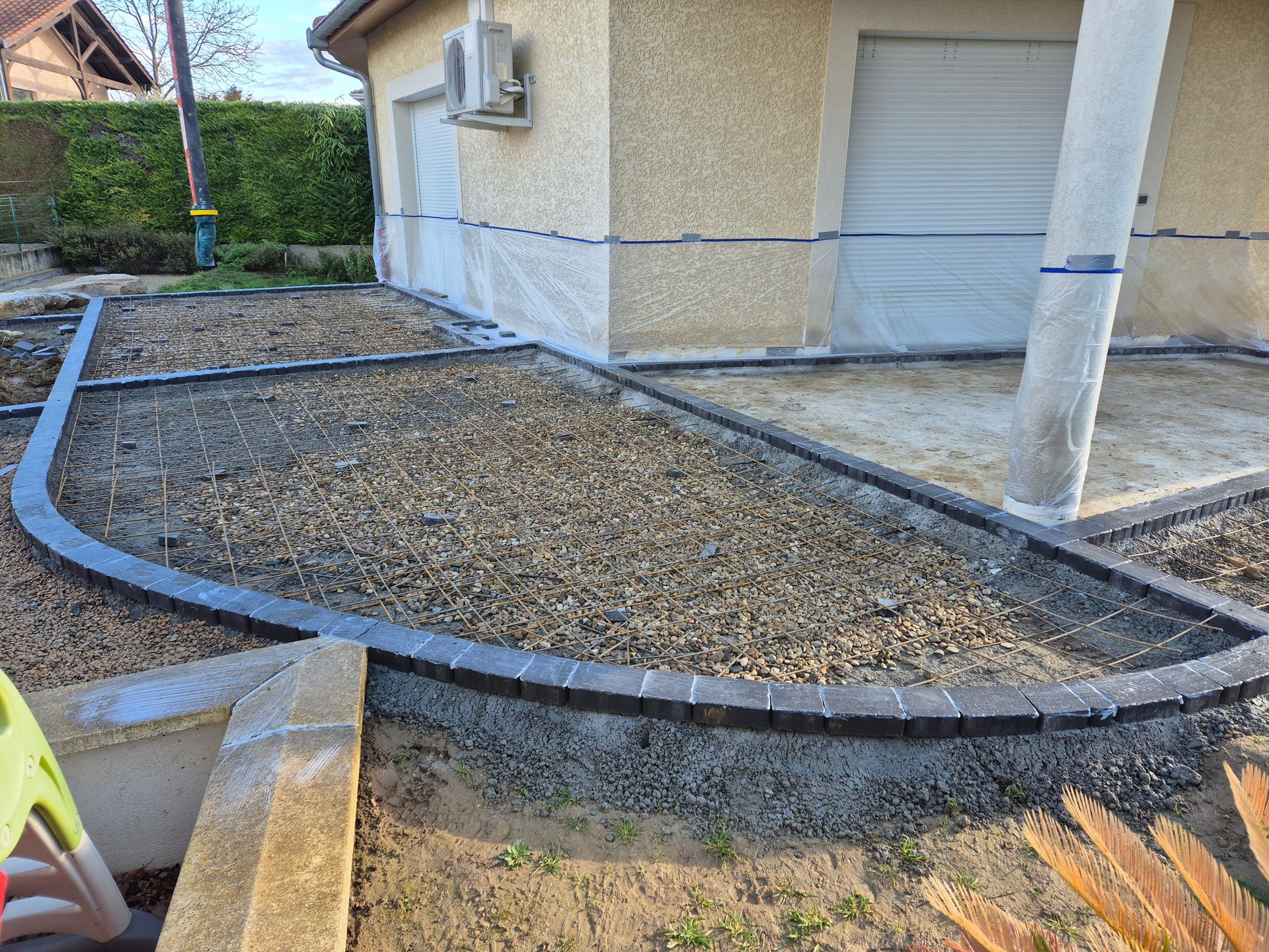 Un parterre de gravier incurvé, bordé de pierres, jouxte une maison et un garage