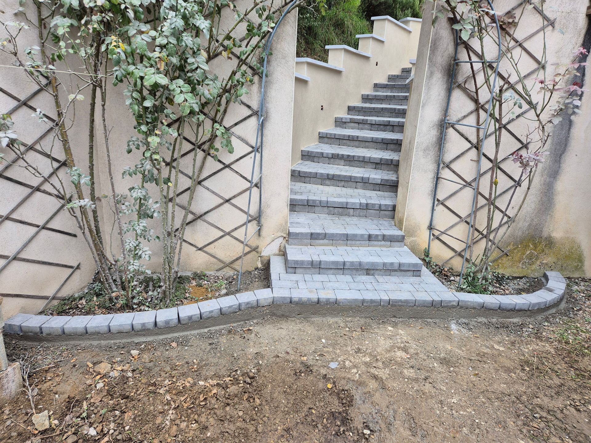 Escalier extérieur incurvé avec marches en pierre grise et vignes grimpantes sur les murs
