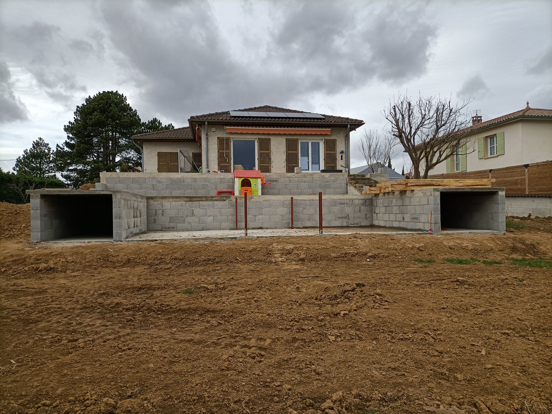 Terre battue et construction en parpaing devant une maison