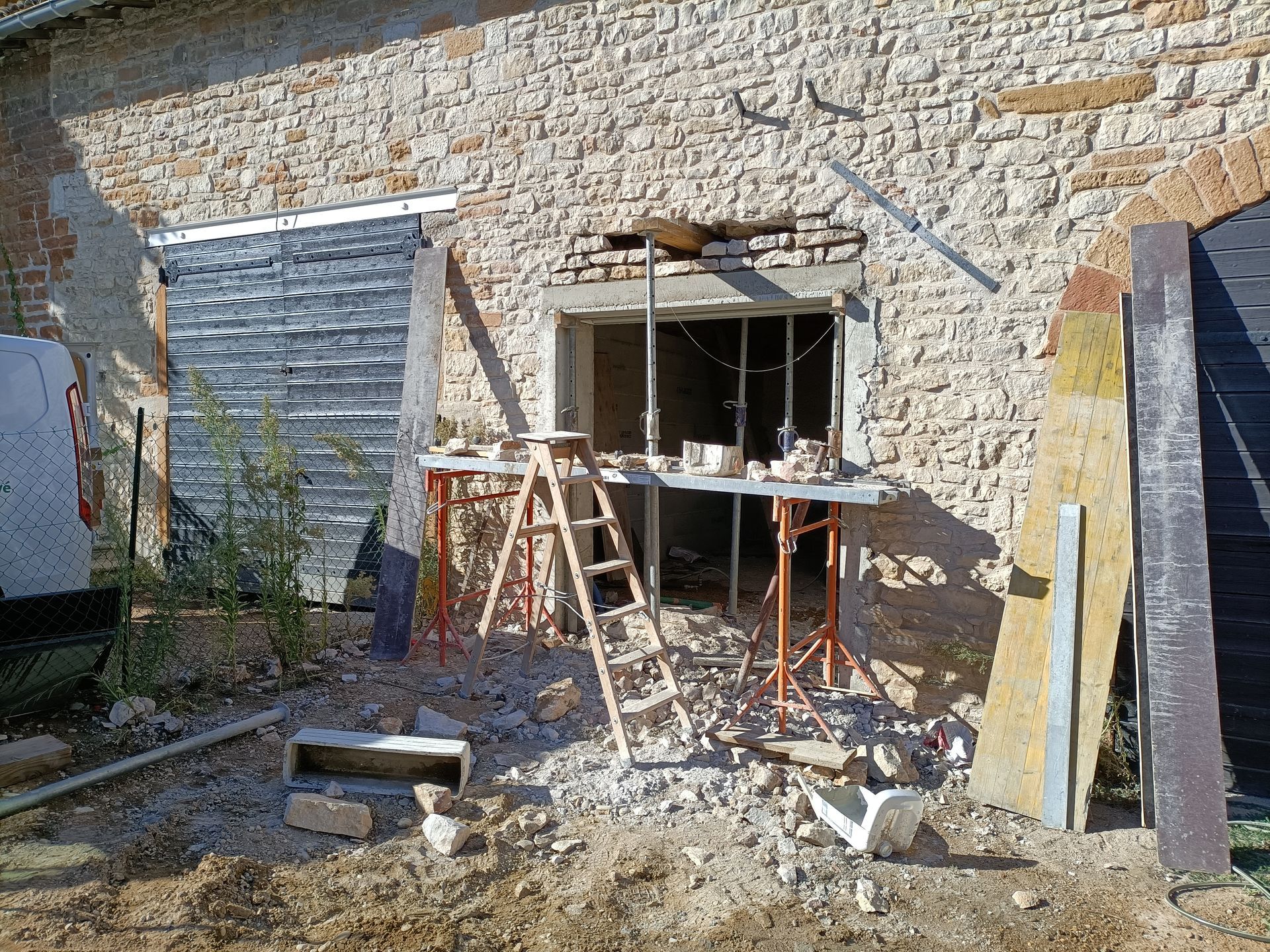Façade d'un bâtiment en pierre en cours de réparation : échafaudages, échelle et matériaux de construction