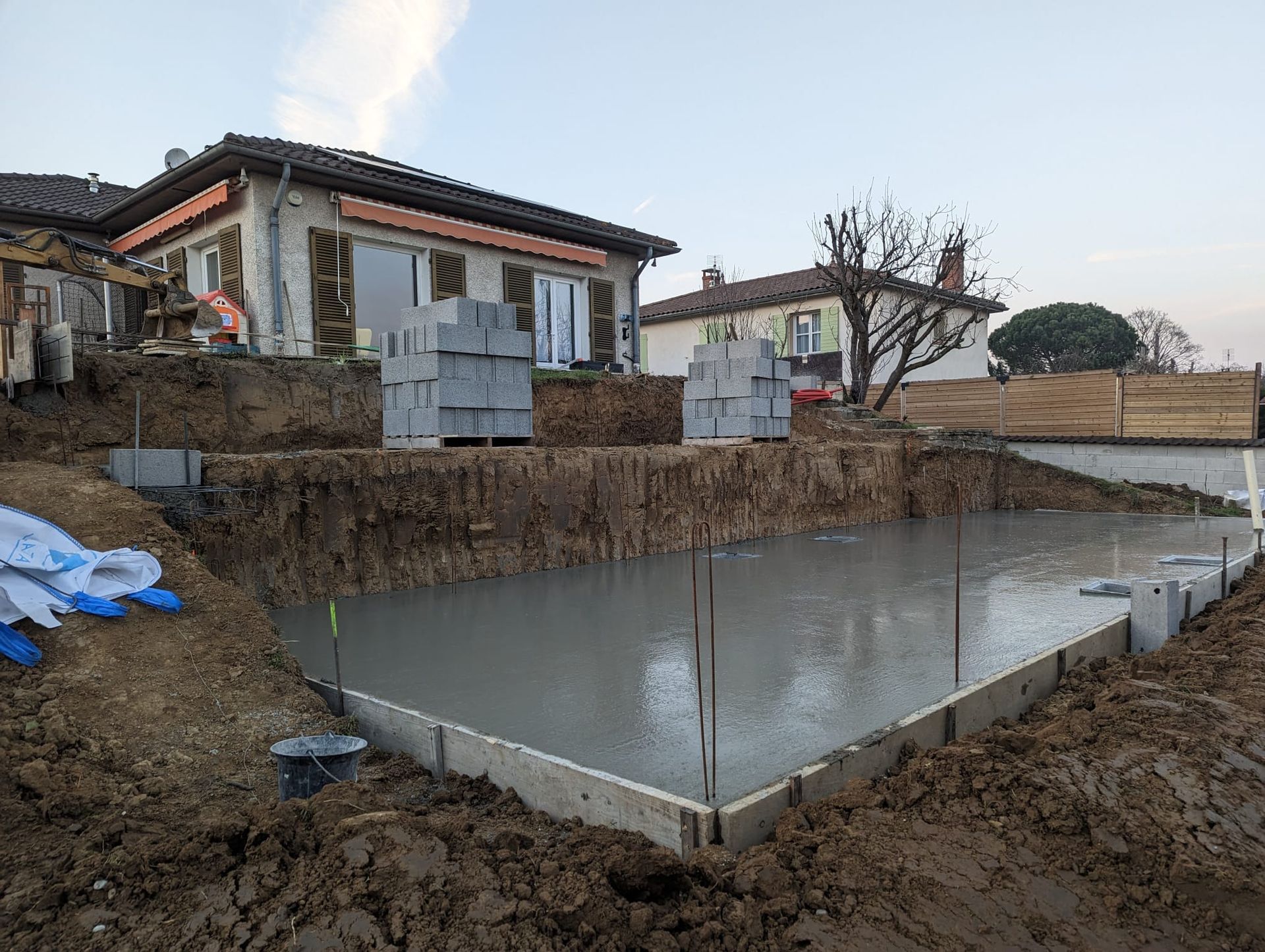 Coulage de dalles de béton sur un chantier de construction de maison avec armatures et sol boueux