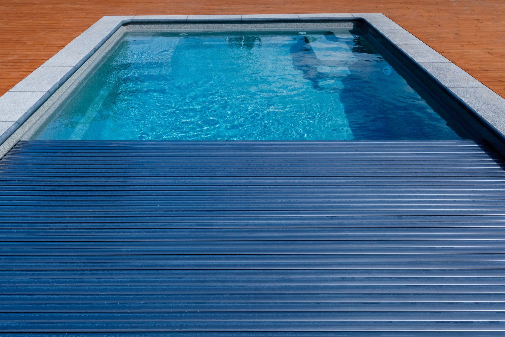 Piscine bleue vide avec une eau ondulée et une couverture bleu foncé fermée au premier plan
