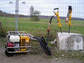 Weingärtner Baumaschinen – Hydraulikstation mit Generator vor einem Bauzaun im Grünen