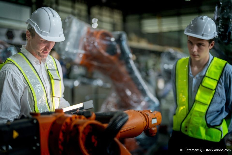Weingärtner Baumaschinen – zwei Arbeiter mit Helm und Warnweste in einer Halle arbeiten an einem Roboterarm