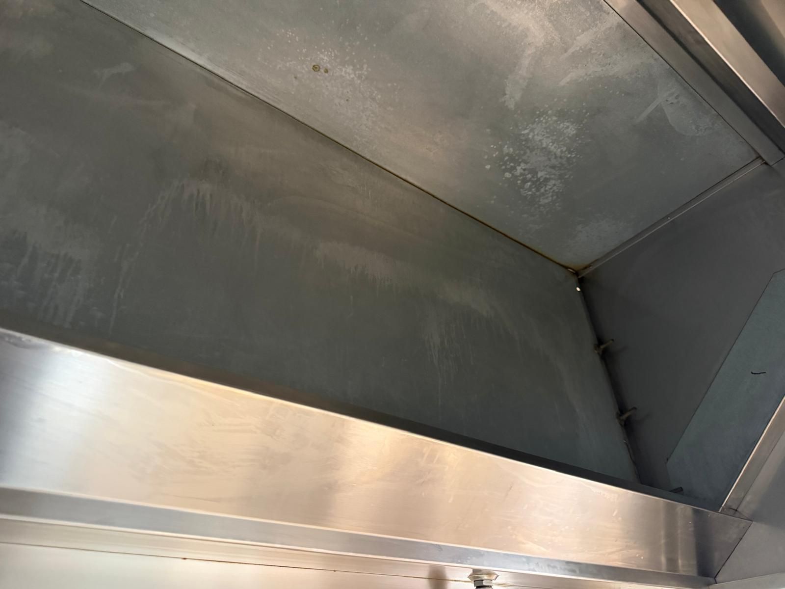 Interior de un conducto de ventilación metálico, con paredes de color gris oscuro y un borde de acero inoxidable cepillado
