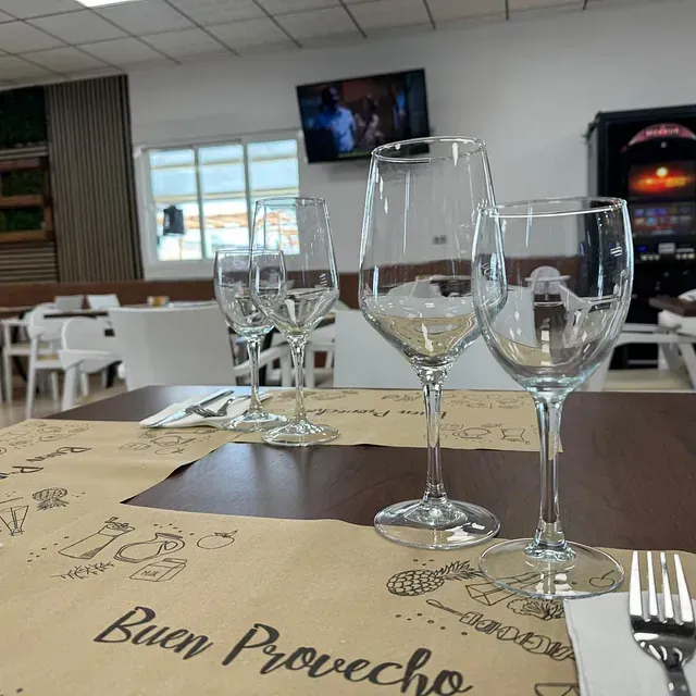 Copas de vino sobre una mesa con un mantel individual que dice buen provecho