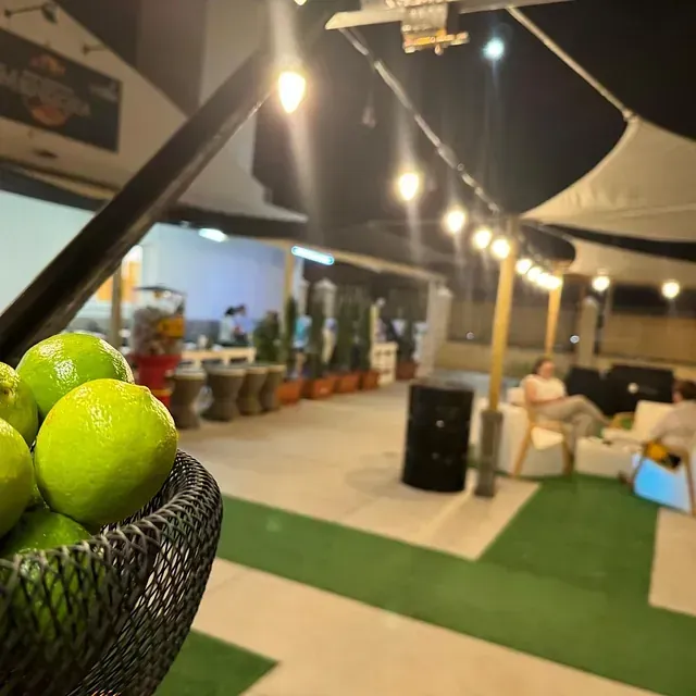 Una persona sostiene un bol de limas delante de un restaurante.