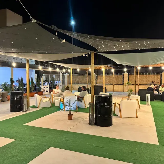 Un grupo de personas están sentadas bajo sombrillas en un patio.