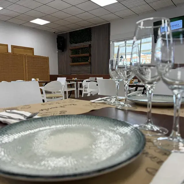 Un plato y copas de vino están sobre una mesa en un restaurante.