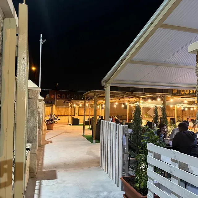 Un grupo de personas está sentado afuera de un restaurante por la noche.