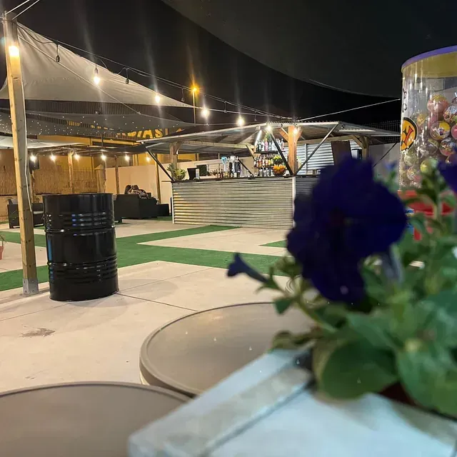 Una mesa con flores y un barril al fondo.