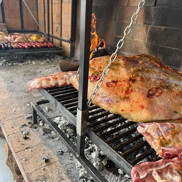 Un gran trozo de carne se está cocinando en una parrilla