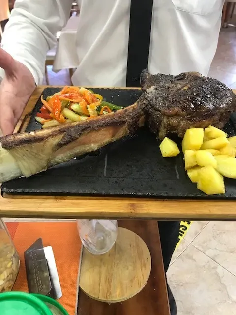 Un hombre sostiene una bandeja de comida que incluye un filete y piñas.