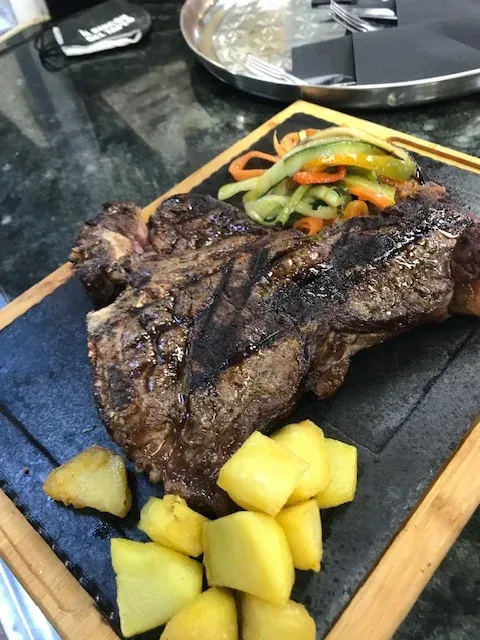 Un filete con patatas y verduras en una tabla de cortar