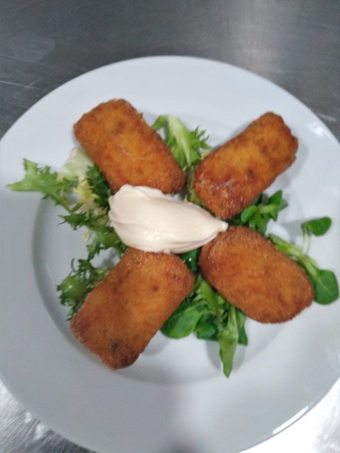 Un plato blanco cubierto con comida frita y lechuga.