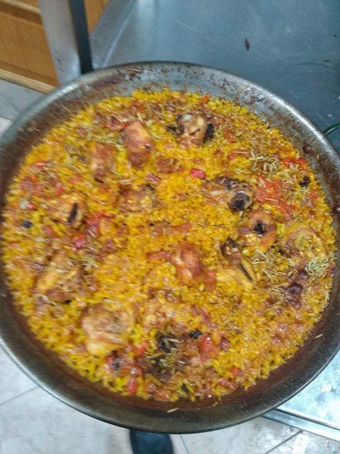 Una sartén llena de arroz y carne está sobre una mesa.