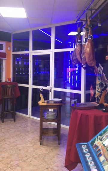 Una habitación con muchas ventanas y una mesa con un mantel rojo.