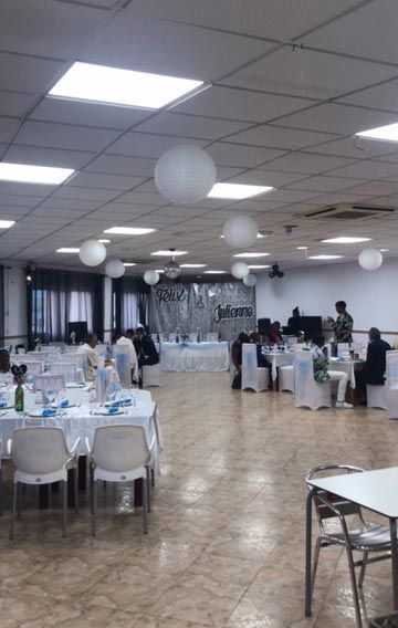 Una gran sala con mesas y sillas y globos colgando del techo.