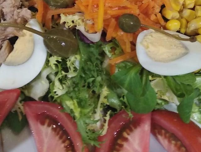 Un primer plano de una ensalada con tomates y huevos en un plato.