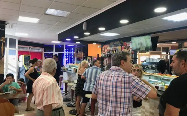 Un grupo de personas están de pie alrededor de una barra en un restaurante.