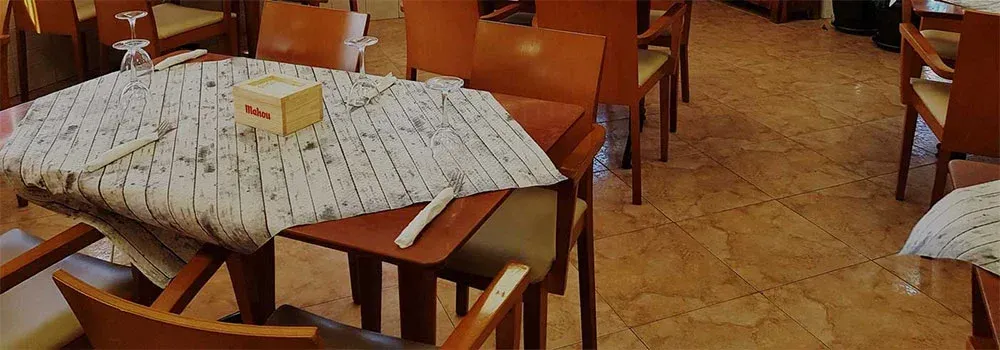 Un restaurante con mesas y sillas y un mantel sobre la mesa.