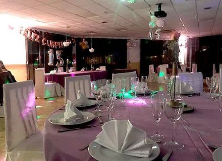 Una sala con mesas y sillas preparadas para una fiesta de cumpleaños.
