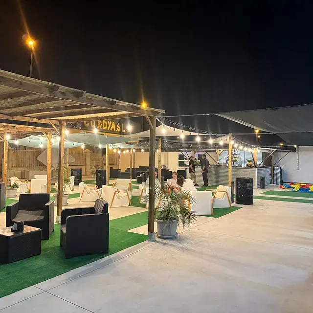 Una gran zona al aire libre con muchas sillas y mesas por la noche.