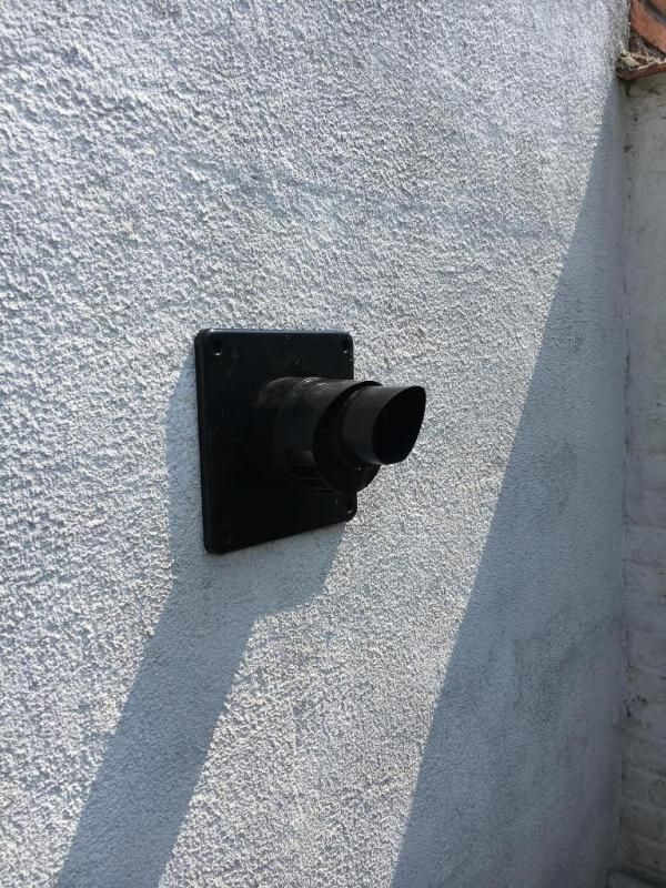 Sortie d'air noire sur un mur en crépi