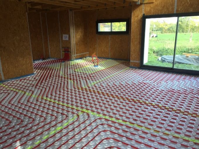 Pose d'un système de tuyaux rouges recouvrant l'intégralité du sol d'une pièce en travaux