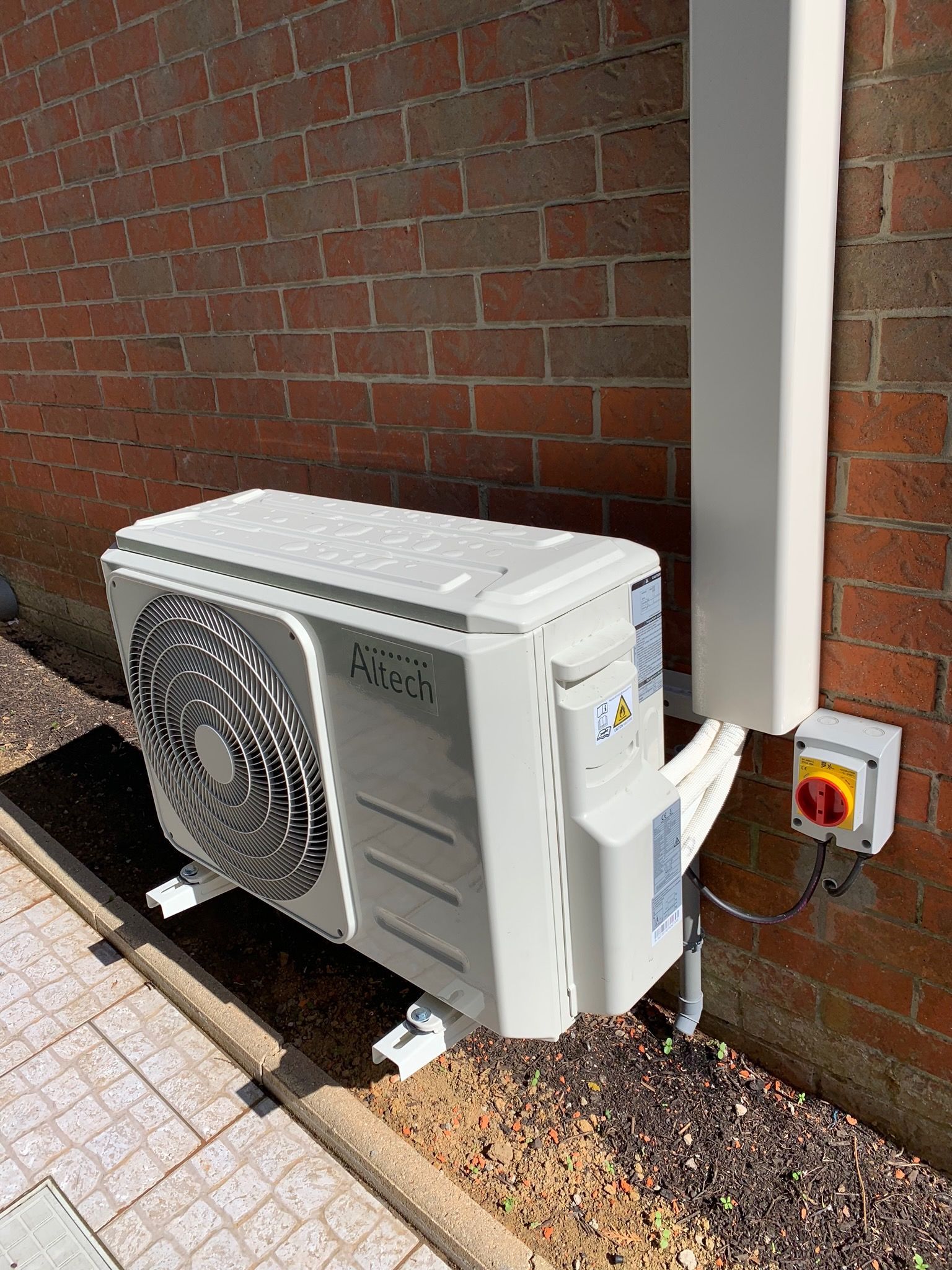 Pompe à chaleur de la marque ALTECH fixée sur un mur en brique