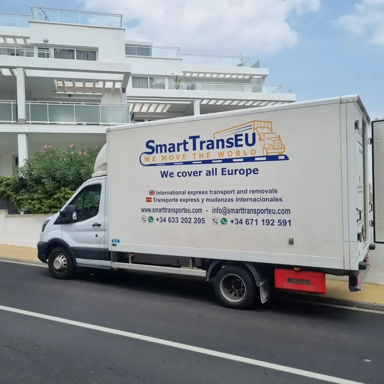 Camión blanco SmartTransEU estacionado en una calle frente a un edificio.