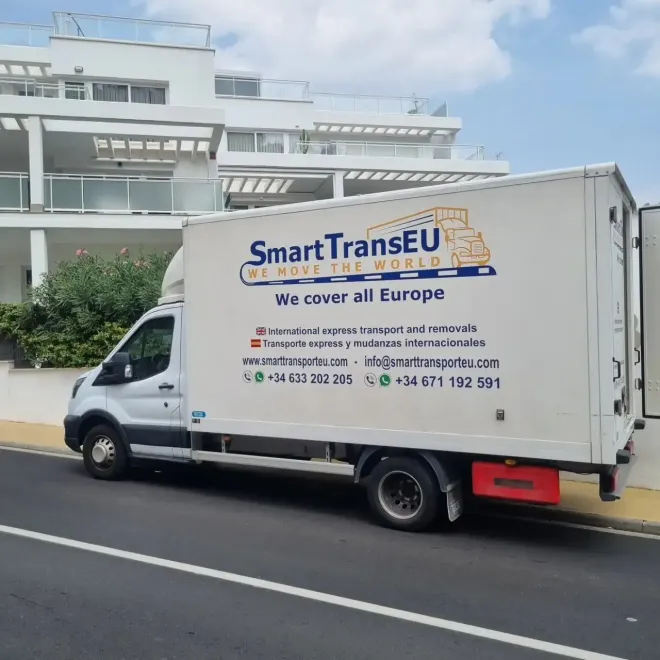 Camión blanco SmartTransEU estacionado en una calle frente a un edificio.