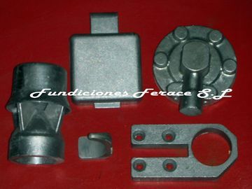 Un montón de piezas de metal se encuentran sobre una superficie roja con las palabras fundiciones ferace sl