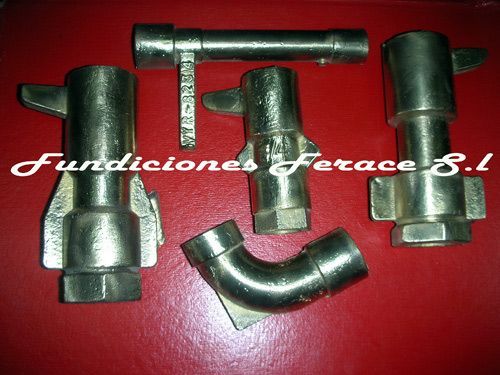 Un montón de tubos de metal están sobre una superficie roja con las palabras fundiciones ferace sl