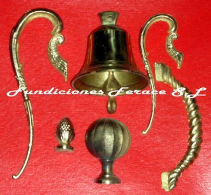 Una campana de bronce reposa sobre una superficie roja con las palabras fundiciones ferace sl debajo.