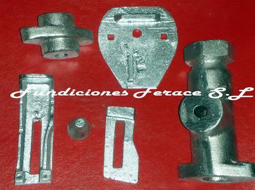 Un montón de piezas de metal sobre una superficie roja con las palabras fundiciones ferace sl