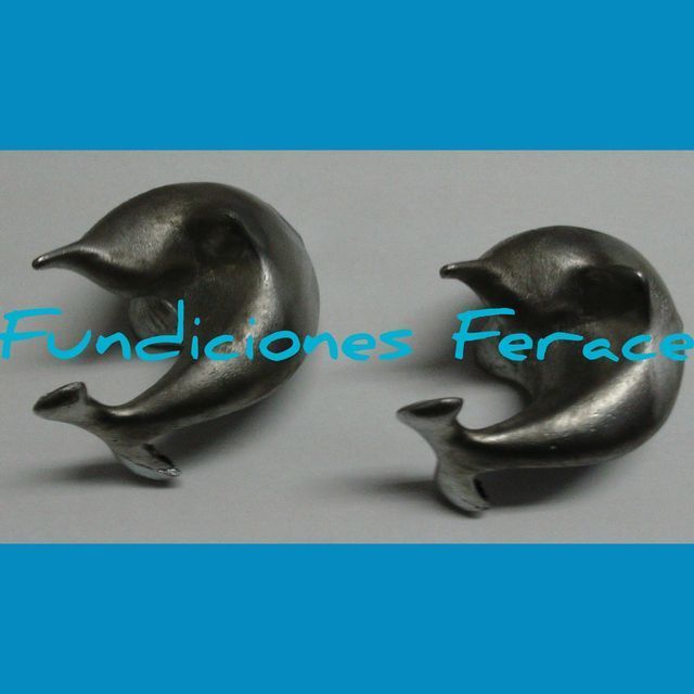 Un par de pendientes con forma de delfín están sobre una superficie blanca.